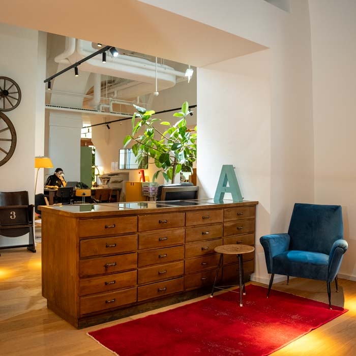 Es ist das helle Ruby Paul Bürogebäude zu sehen. In der Mitte des Bildes steht eine Büroinsel.